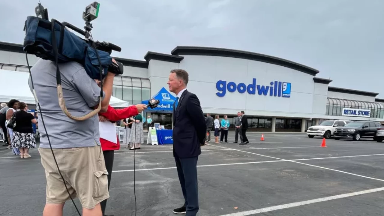 A news crew interviewing a man in front of a Goodwill retail store, capturing a community event or press coverage.