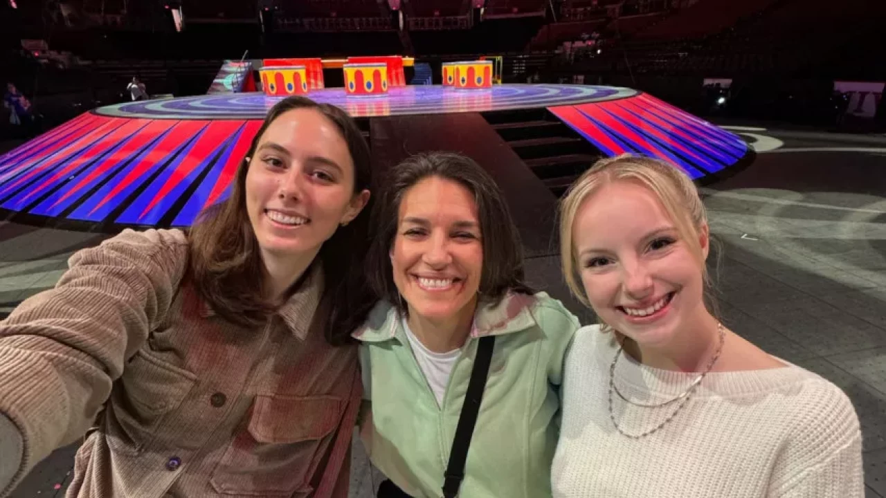 Sarah, Lydia, and Mia smiling for a selfie in front of a colorful stage setup, at Ringling Bros.